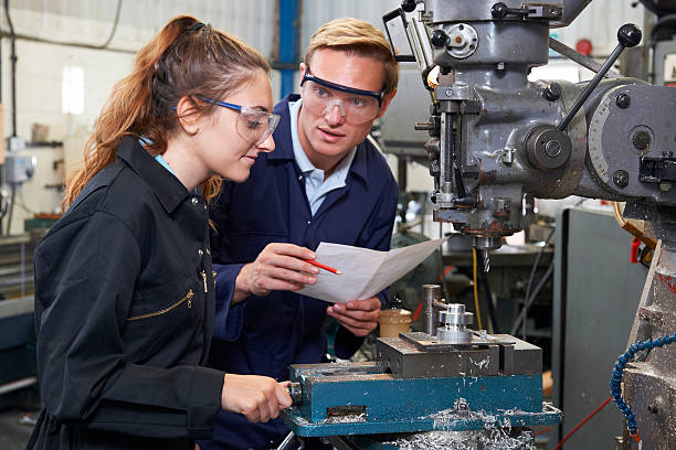 istock Engineer Showing Apprentice How to Use Drill In Factory 476222416