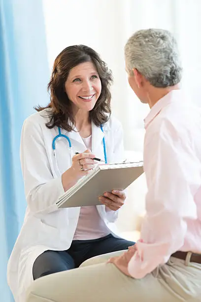 Photo of Happy Doctor With Clipboard Looking At Patient