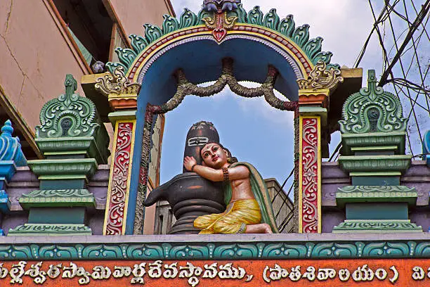 JANUARY  27, 2015, VIJAYAWADA, ANDHRA PRADESH, INDIA - Bhakta hugs Shiva-Linga, sculpture over the gate of the Hindu temple
