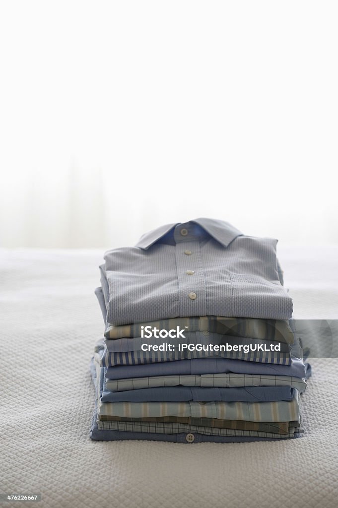 Ferro e camisas dobradas na cama - Foto de stock de Cama royalty-free