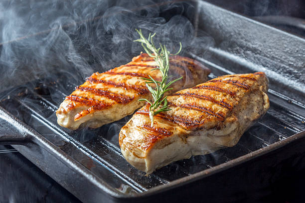 Chicken Breast with rosemary in pan Two golden fried pieces of chicken breast in a griddle pan with rosemary griddle stock pictures, royalty-free photos & images