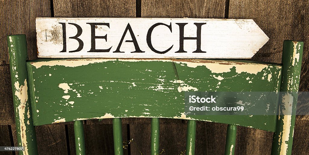 Beach sign arrow beach sign sitting on top of a distressed green chair Arrow Symbol Stock Photo