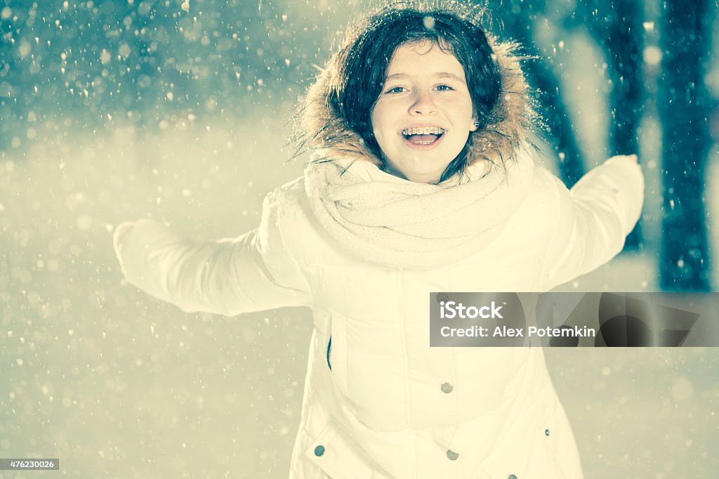 Pretty teenager girl in the white jacket under snowfall Pretty teenager girl in the whire jacket under the snowfall Bracket - Household Fixture Stock Photo