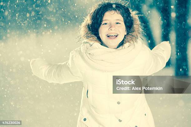 Pretty Teenager Girl In The White Jacket Under Snowfall Stock Photo - Download Image Now