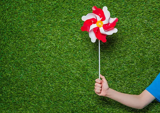 Photo of Human hand holding pinwheel over grass