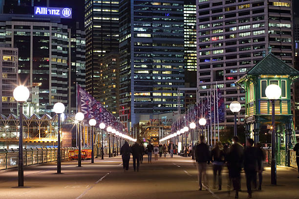 Sydney, Australia - June 4, 2015: Pedestrians walking across The Pyrmont Bridge, a swing bridge across Cockle Bay, Darling Harbour, towards Sydney and the CBD buildings and offices.