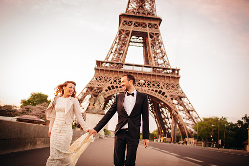 Young couple together in front of an Eiffel Tower in Paris, France - on their first morning as married couple. 