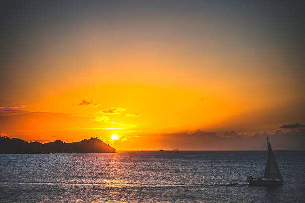 Yacht sailing out of bay at sunset time.