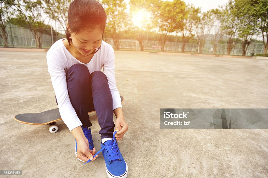Jeune femme assis sur un skate essayer de nouvelles chaussures - Photo de Activité libre de droits