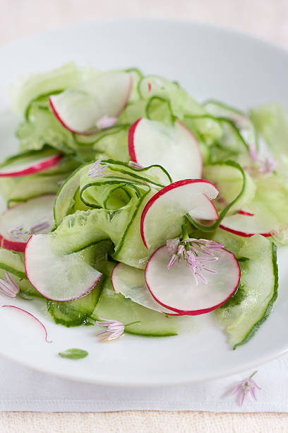 Spring salad - cucumber, radish and chive flowers stock photo