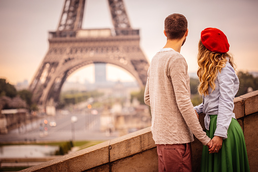 Photo of young stylish couple in front of the Eiffel tower in Paris-France, holding hands.