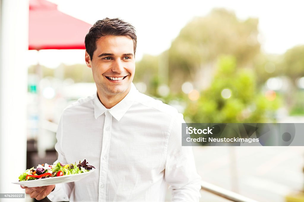 Cameriere guardando lontano mentre Holding Insalata nel ristorante - Foto stock royalty-free di 20-24 anni