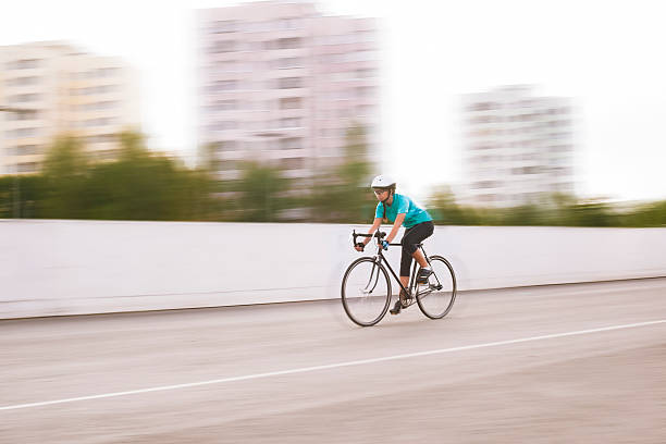 jovem atleta feminina num movimento de corrida turva bicicleta. imagem - racing bicycle cyclist sports race panning imagens e fotografias de stock