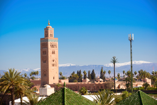 Marrakech Koutoubia minaret, rooftop skyline with Atlas Mountains.