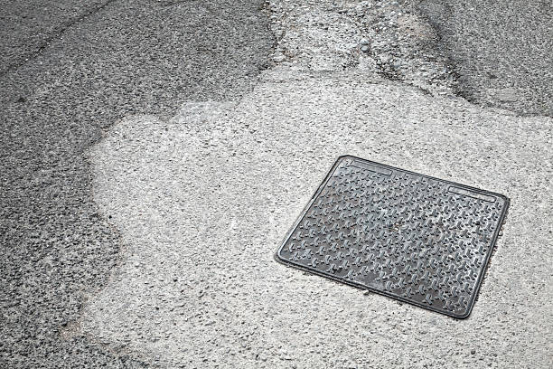 istock Square metal hatch on asphalt road 476255595
