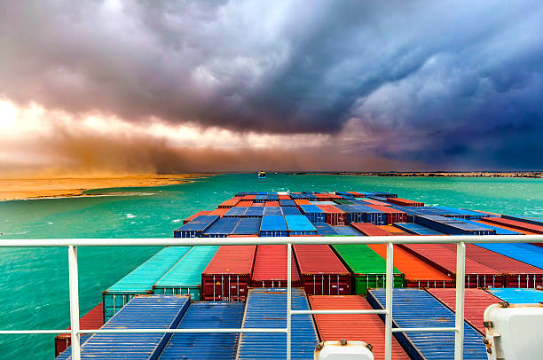 Suez Canal - Ships passing and desert storm approaching Desert Storm arising in Suez Canal, Egypt. Container Ship in the fore ground. canal stock pictures, royalty-free photos & images