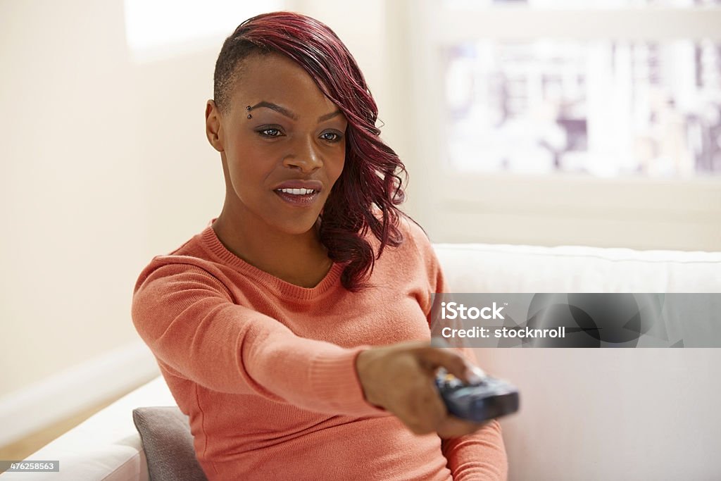 Hermosa mujer mira televisión en su casa - Foto de stock de 20 a 29 años libre de derechos