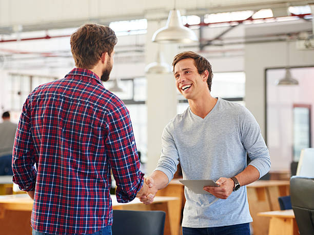 The beginning of great business Shot of two young businessmen shaking hands in a casual officehttp://195.154.178.81/DATA/i_collage/pu/shoots/804770.jpg casual handshake stock pictures, royalty-free photos & images