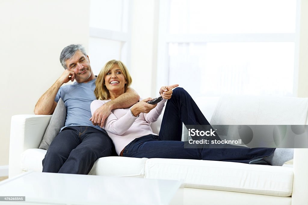 Szczęśliwy Dojrzała para siedzi razem oglądanie telewizji - Zbiór zdjęć royalty-free (40-44 lata)