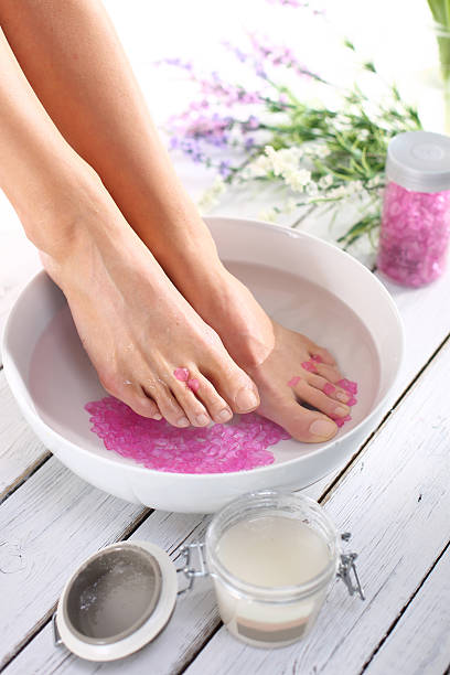 Therapeutic foot bath A woman washes the feet in a bowl of water and salt to the foot home pedicure stock pictures, royalty-free photos & images