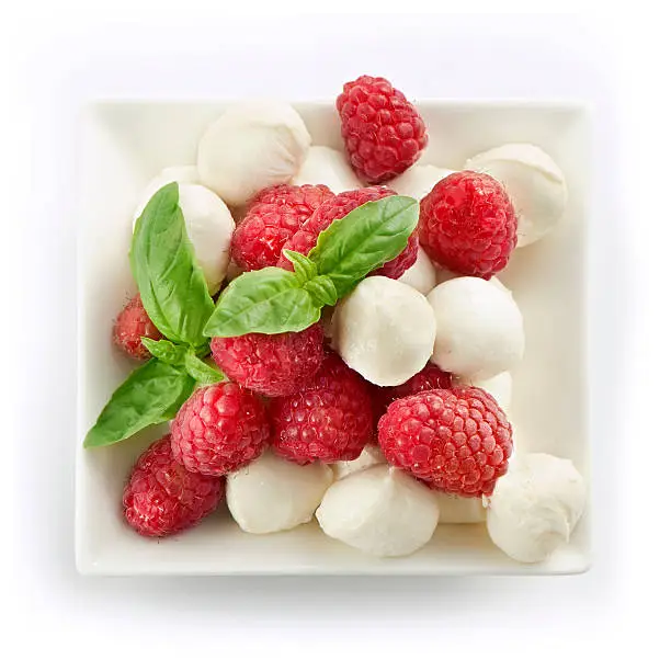 delicious raspberry salad with mozarella and basil served in a square bowl shot from above