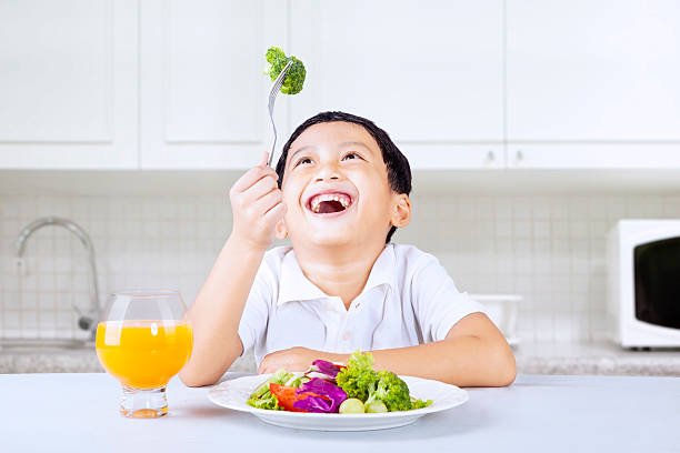 istock Happy boy eat brocoli in kitchen 476269912