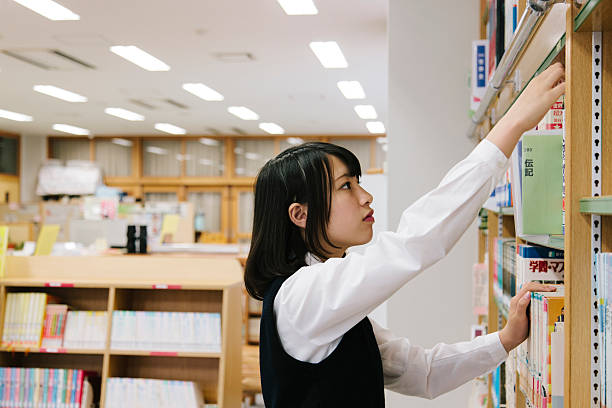 istock Japanese high school, library. Choosing a book, female student 476270628