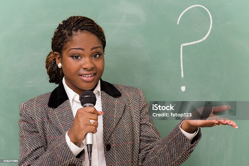 Business:  Businesswoman wearing suit speaking to co-worker audience. Businesswoman wearing suit and using microphone to do presentation for executives.   20-24 Years Stock Photo