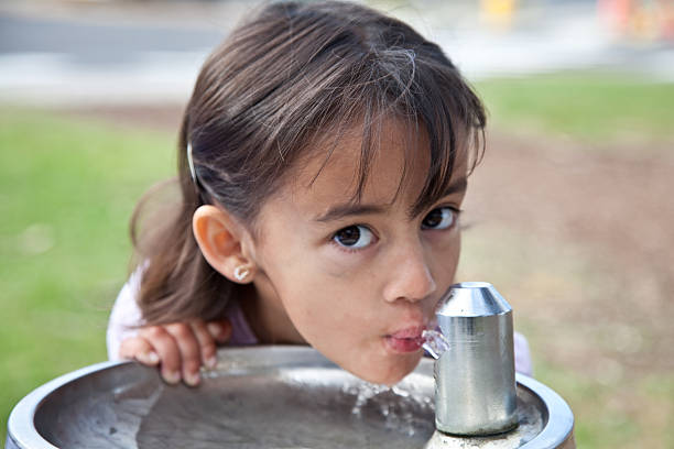 Little girl drinking from a water fountain