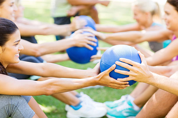Friends Exercising With Medicine Balls In Park