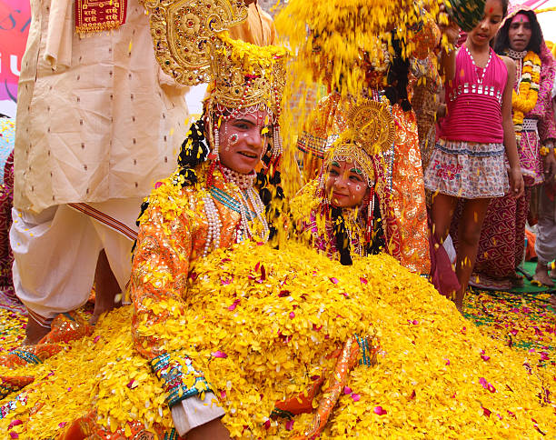 Phoolon Ki Holi : Holi with flowers Delhi, India- March 19, 2011: A long forgotten tradition was brought alive at "Delhi Haat" located in New Delhi. The tradition of playing Hoil with flowers. People threw petals of marigold, jasmine and chrysanthemums on each other. In the picture, a pit of  young boy and girl poses as Lord Krishna and Radha.  Flowers are being showered on the duo. radha krishna stock pictures, royalty-free photos & images