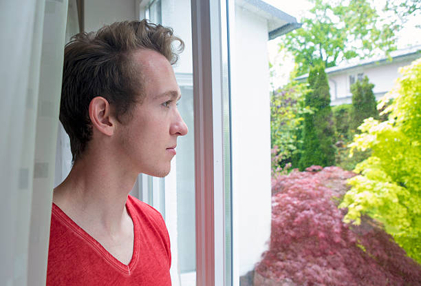 istock young blond man looking out of window 476309084