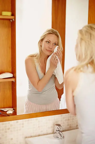 A beautiful young woman drying her face in front of the mirror