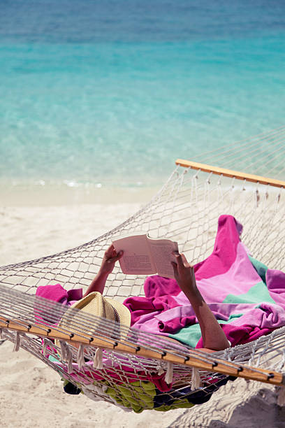 istock unrecognizable woman reading a book in hammock at the beach 476317089