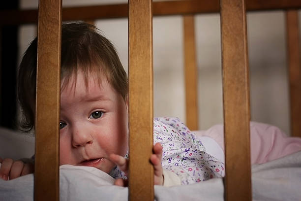istock child playing in the bed behind bars 476319588