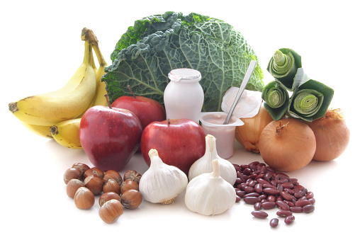 Prebiotic foods including yogurt, vegetables and pulses over a white background. Healthy for immunity and the gut.