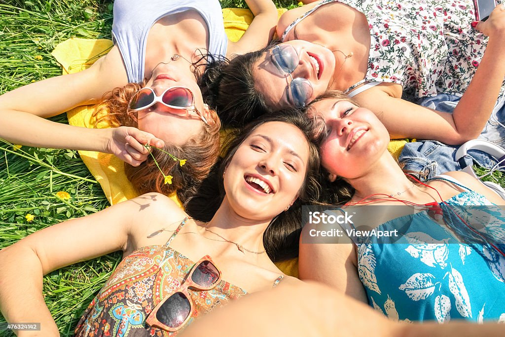 Multiracial girlfriends taking selfie at countryside picnic outdoors Multiracial girlfriends taking selfie at countryside picnic - Happy friendship concept and fun with young people and new technology trend - Sunny afternoon color tones - Framed hand holding smartphone Teenager Stock Photo