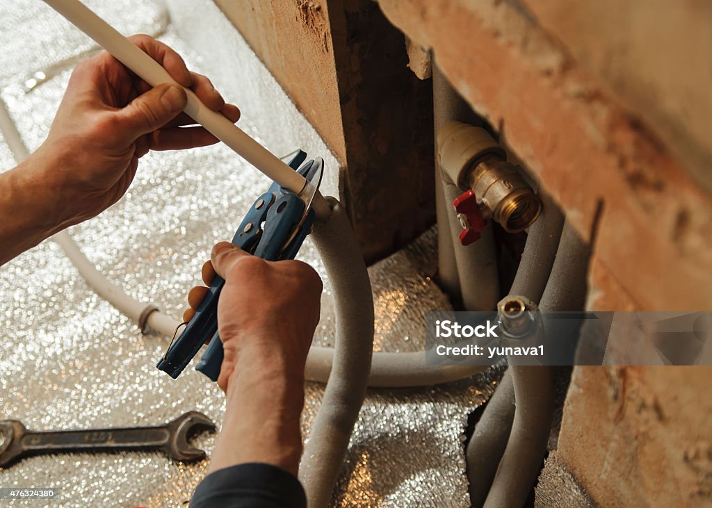 Heated floor Heated floor. Man with scissors cuts the excess pipe. 2015 Stock Photo