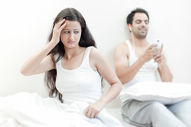 tensed femme agacée avec son inattention mari sur le lit. - relationship difficulties audio photos et images de collection