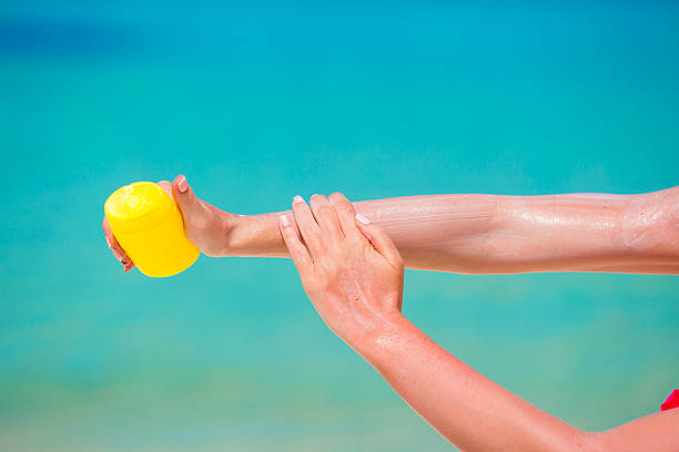 istock Female hands with suncream bottle background blue sea 476328252