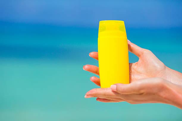 istock Female hands with suncream bottle background blue sea 476331296