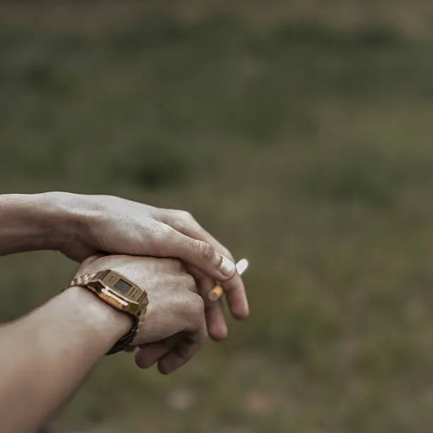 A casio watch and smoking cigarette against a dark green background.