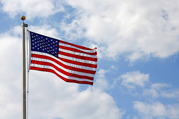 istock American Flag in front of Cloudy Blue Sky 476338892