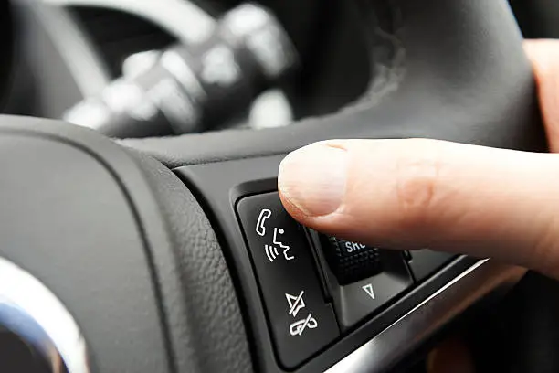 Close Up Of Hand Pressing Car Bluetooth Control On Steering Wheel