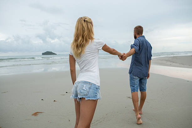 casal jovem caminhando na praia - rear view back men reaching - fotografias e filmes do acervo