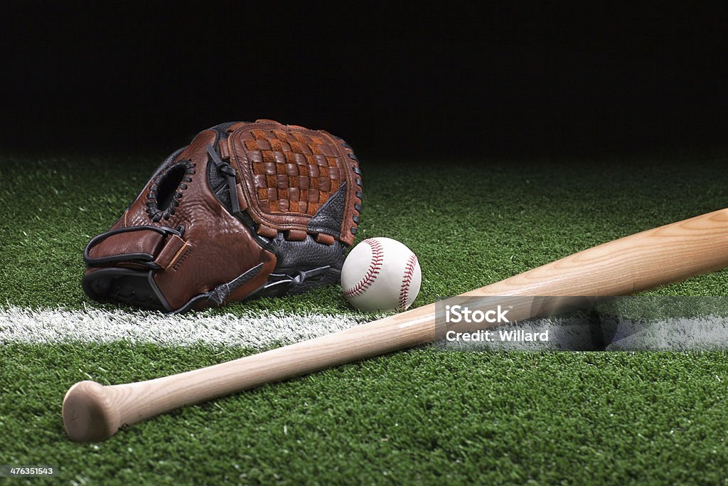 Baseball with mitt and bat on green grass at night Baseball with mitt and bat on green grass with stripe at night Baseball Bat Stock Photo