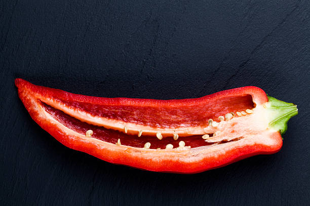 Sliced red pepper half on dark stone plate stock photo