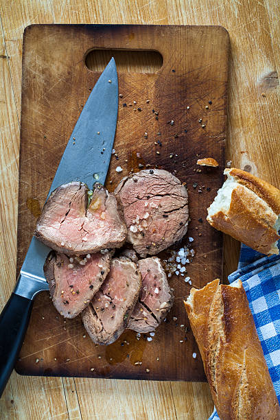 Roast beef on cutting board with salt and pepper stock photo