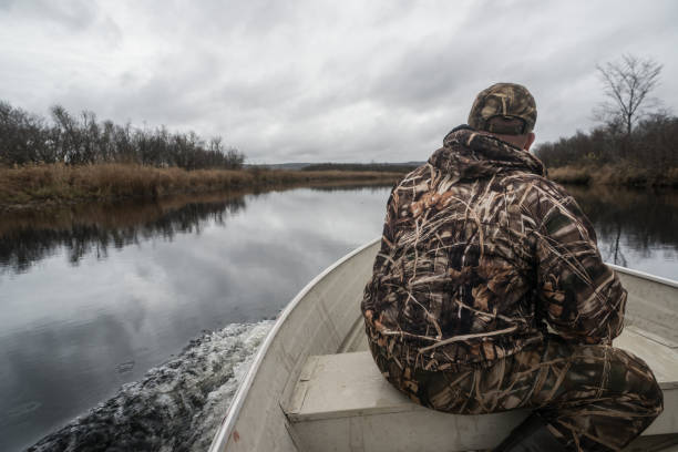 Glenelg, Canada - November 1, 2012: A hunter in full camouflage travels down the St. Mary's River in search of migratory Canada geese and ducks.