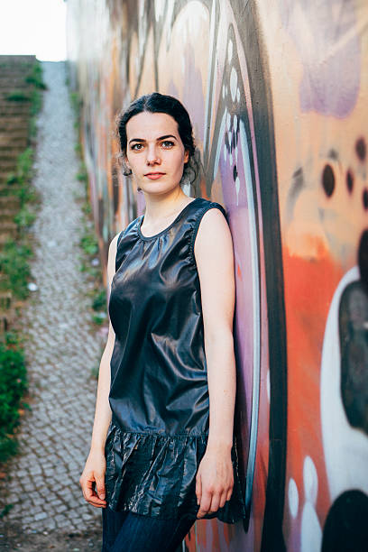 istock urban portrait: young woman leans against graffitti wall 476370478